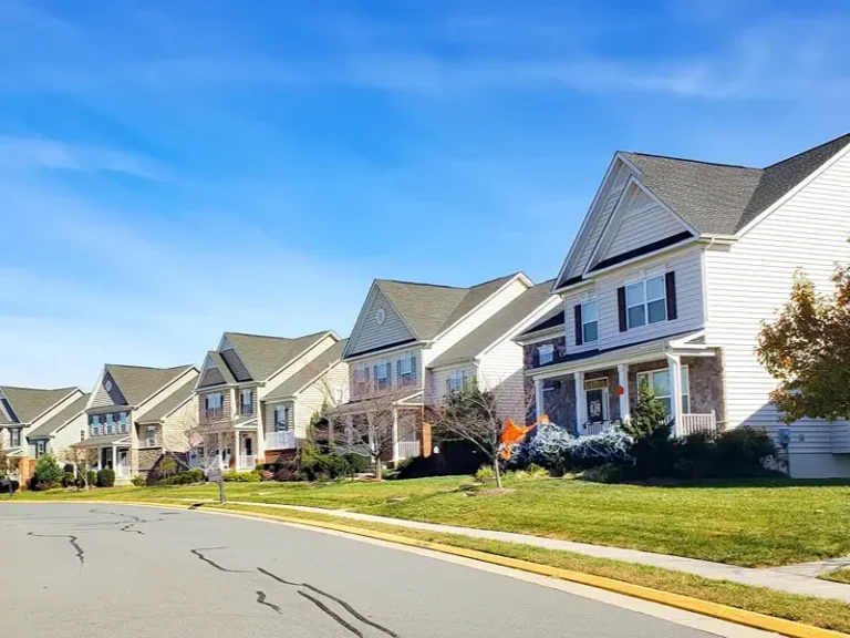 Suburban houses along a curved street under a blue sky.