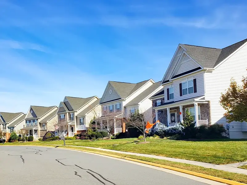 Suburban houses along a curved street under a blue sky.