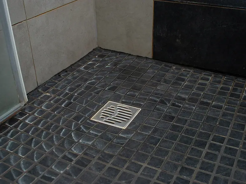 Tiled shower floor with a square drain.