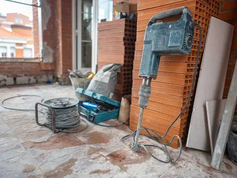 Power drill leaning against stacked bricks at a construction site.